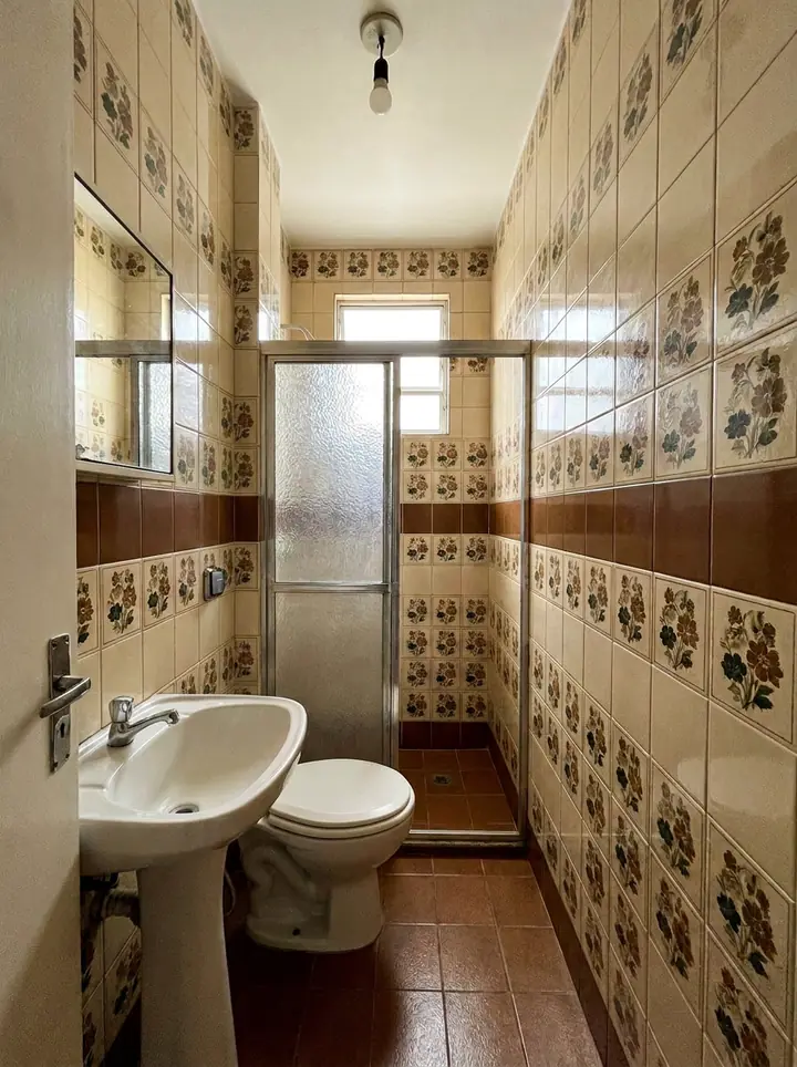 Banheiro antes, com azulejo de florzinha, faixa marrom e piso marrom